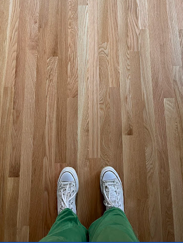 photo shows a person standing on refinished hardwood flooring in converse sneakers
